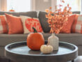 Lovely living room fall decor, complete with pumpkins, gourds, and festive orange throw pillows.
