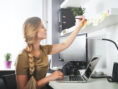 Woman working in her home office, surrounded by organized tech.