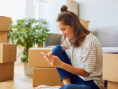 Young woman reads through helpful moving tips on her phone to take the stress out of her move.