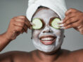 Young woman pampers herself with facial cream and cucumber slices as part of her home spa day.