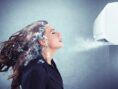 Woman's face and hair collects ice as she stands in front of an ultra-strong A.C. unit.