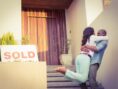 Happy couple embraces outside their new house.