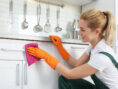 Woman cleans the handles on her kitchen cupboards — a commonly missed spot when people clean their apartments.
